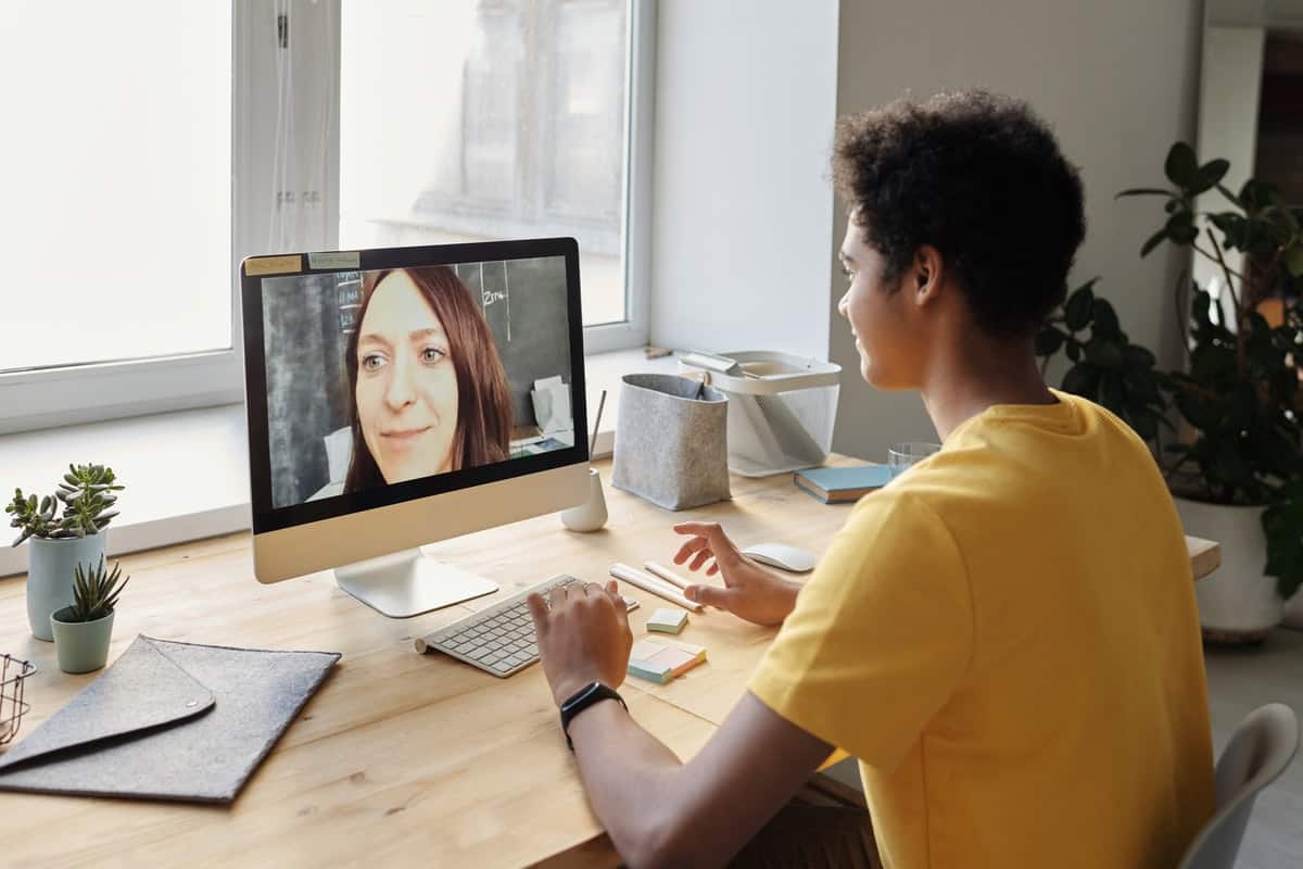 a male student attending an online class with female teacher