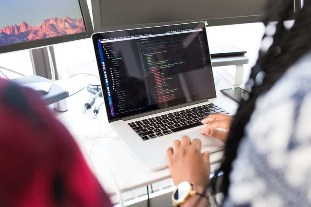 Two people reviewing lines of code on a laptop How to Learn to Code for Free