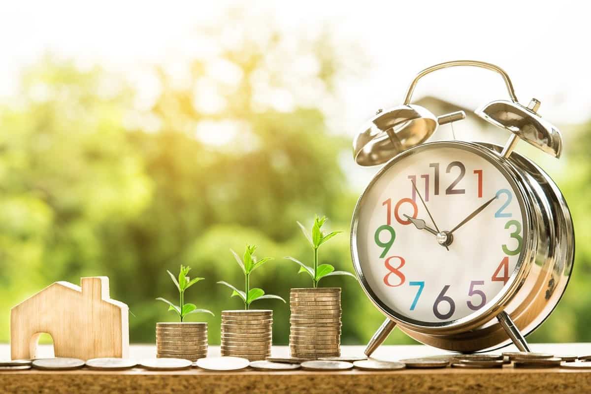 Growing stacks of coins with plants next to a clock. What Are Income Share Agreements?