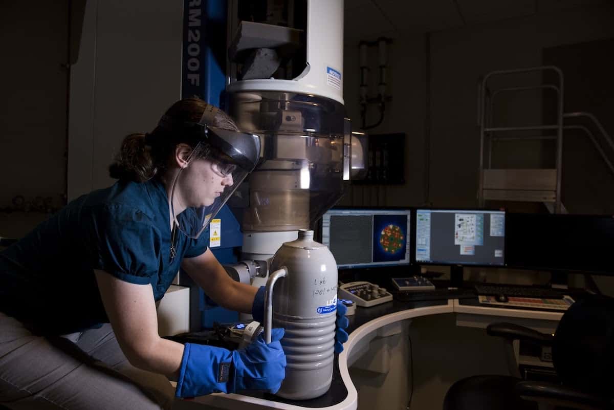 A woman scientist laden with protective gear works on a device women in stem careers