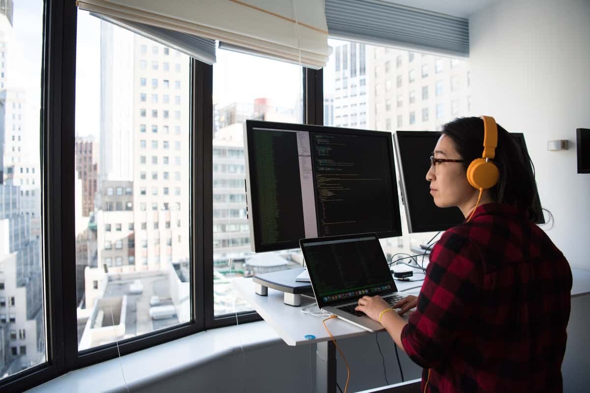 Woman sitting in front of three computers with headphones on Coding Bootcamp for Women