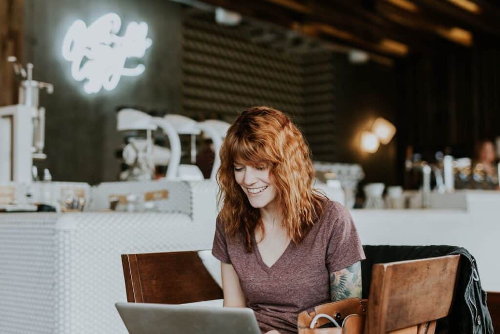 A woman smiling while working on her laptop is it too late to change careers