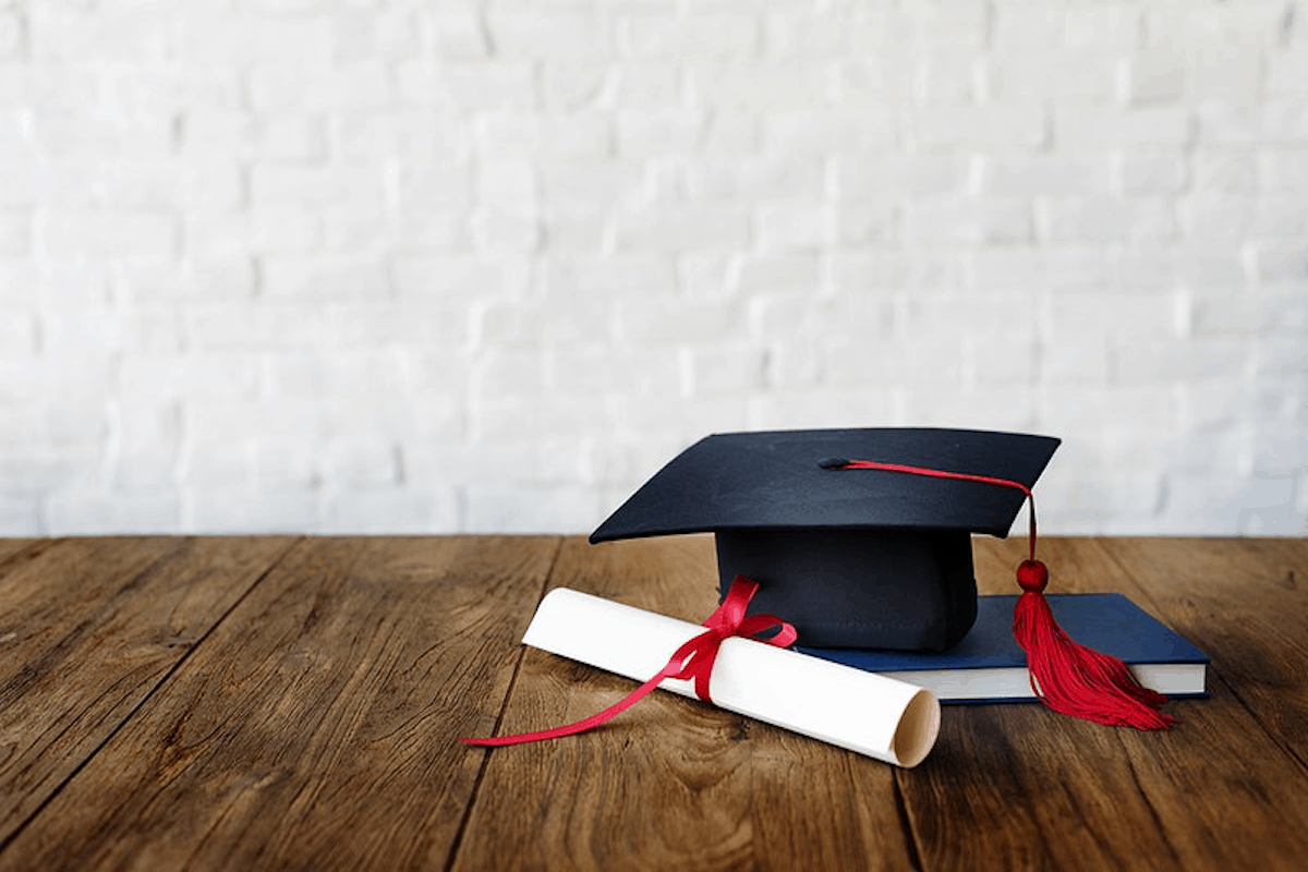 Graduation cap with a rolled diploma on a wooden table tips if you are considering dropping out of college