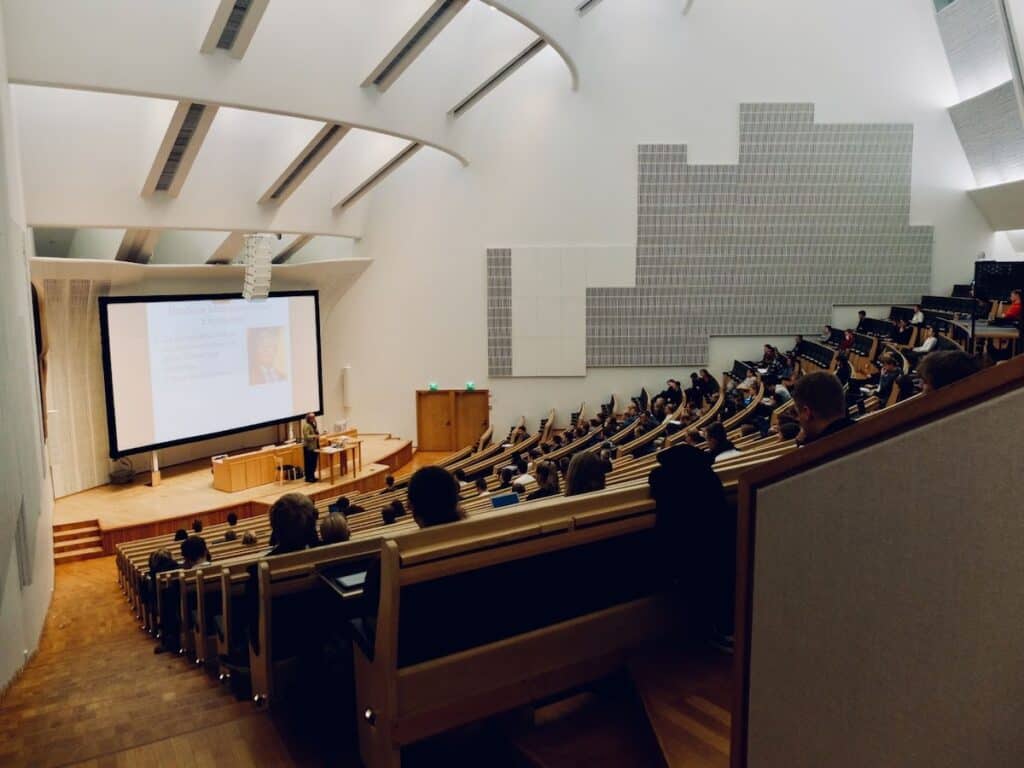 Students in an auditorium-style classroom facing a projector screen. Is College for Everyone