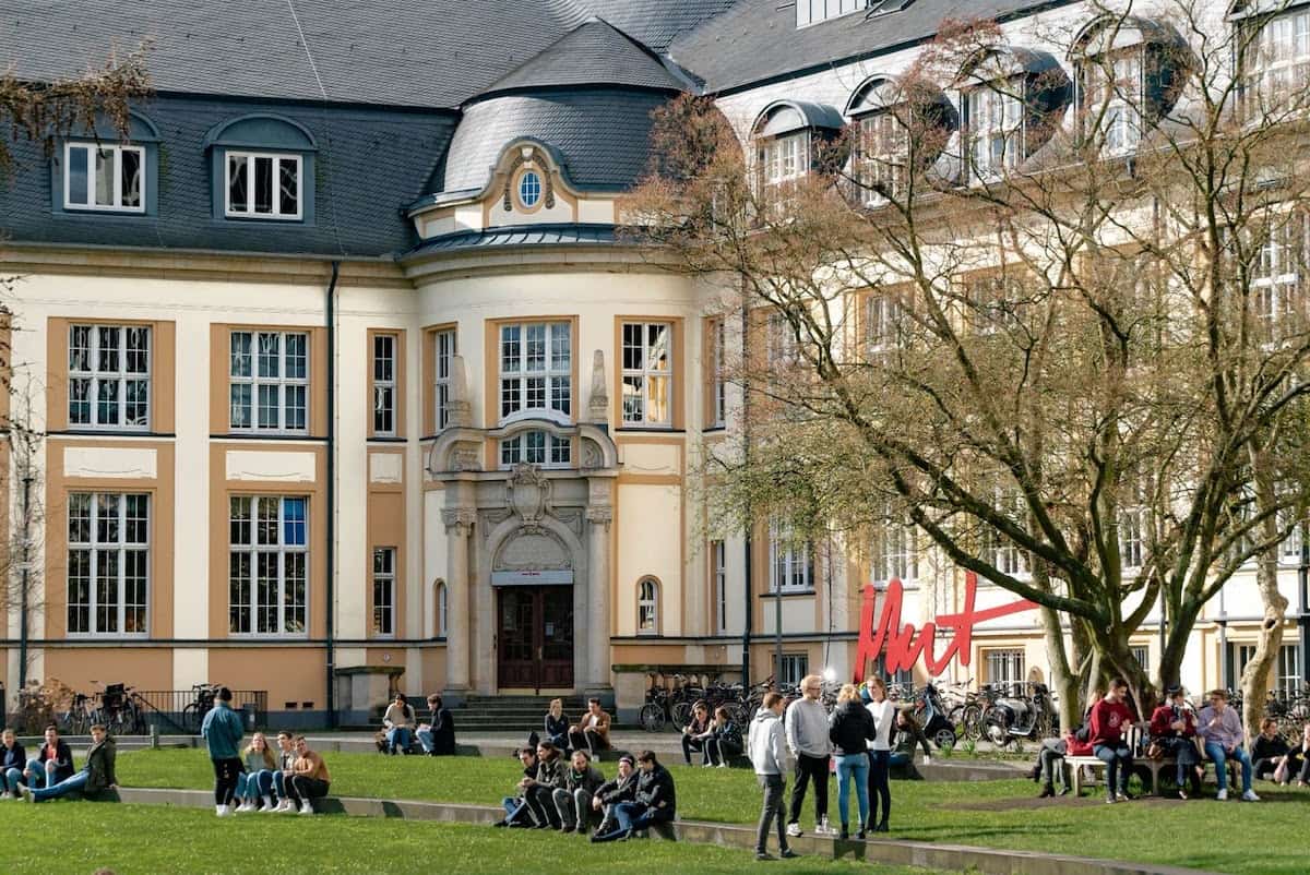 Students sitting near a college building Is College for Everyone