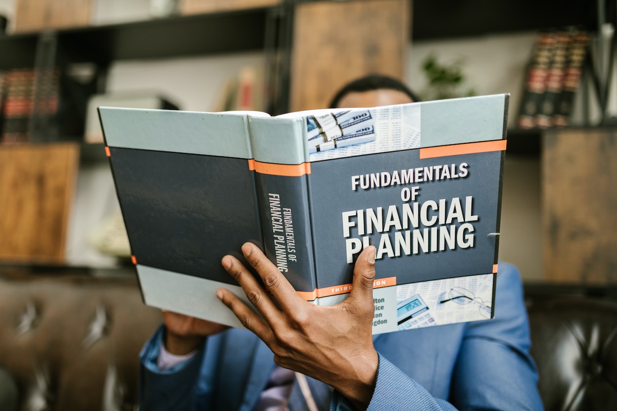 A man holding a textbook titled Fundamentals of Financial Planning.
