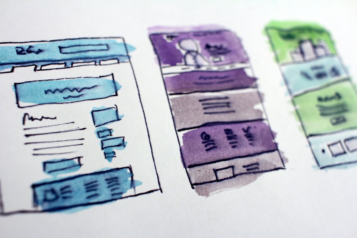 Three sketched website design drafts on a piece of paper