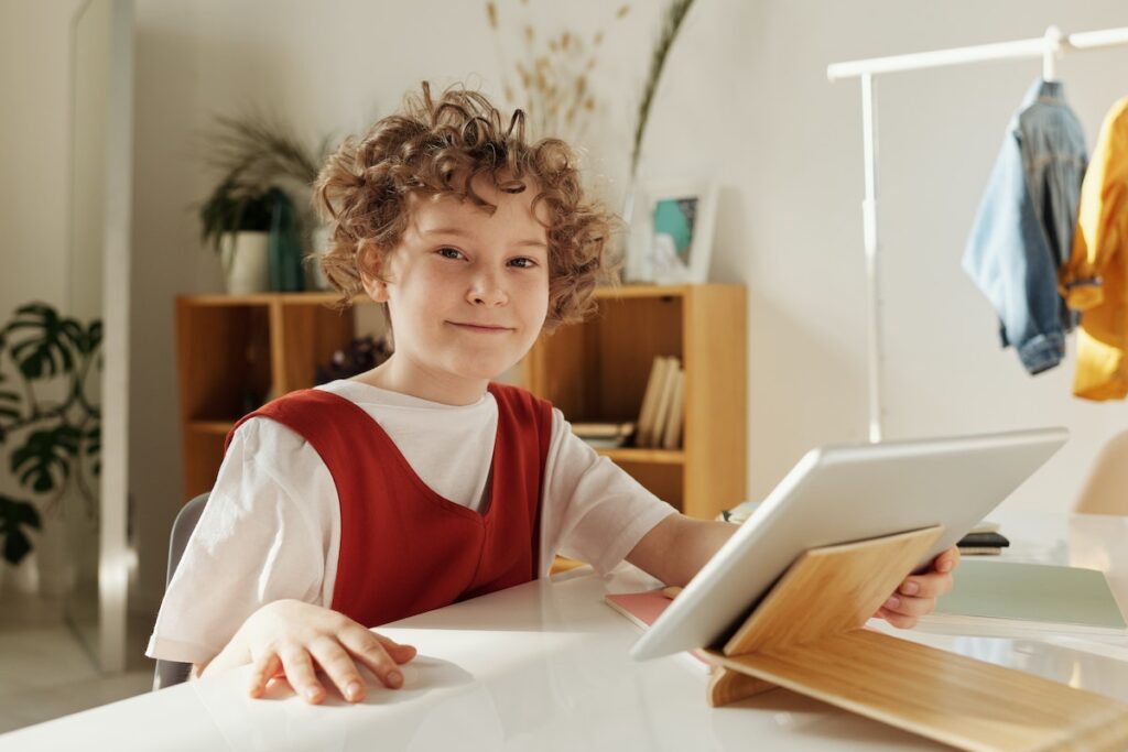 A child smiling and using a digital tablet to learn about animation techniques. 
