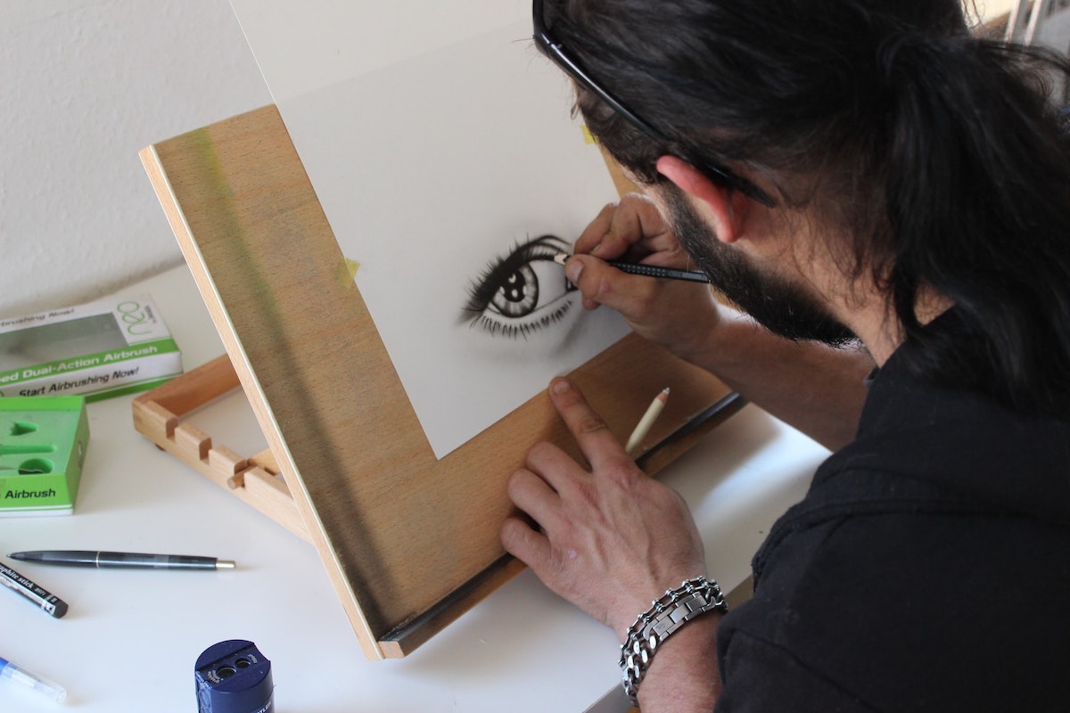 An artist sketching with a black marker on plain paper.