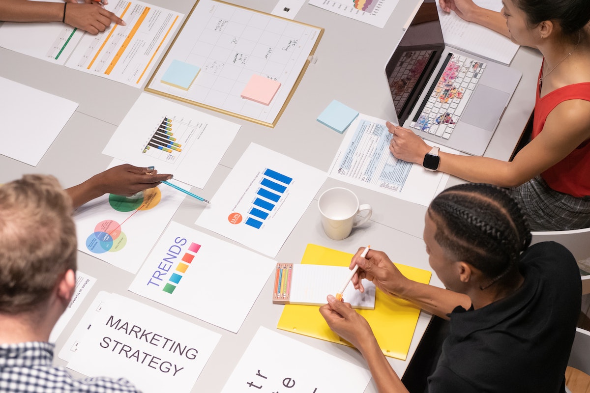 A group of people discussing their marketing strategy with business papers laid out on the table.