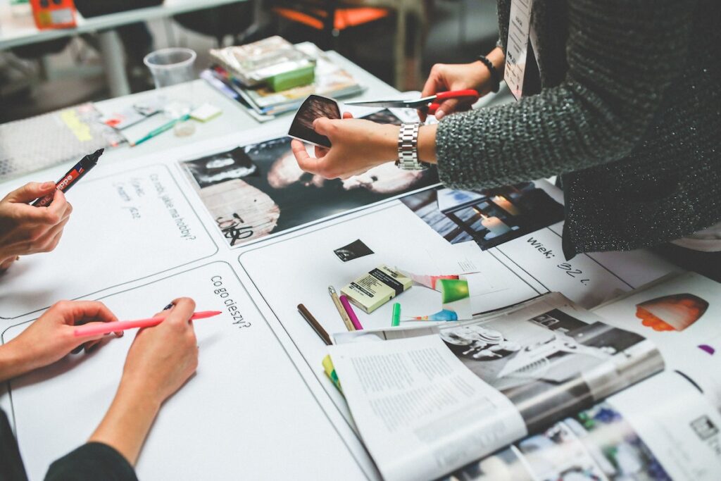 A group of people are working on a project with lots of paper and stationery.